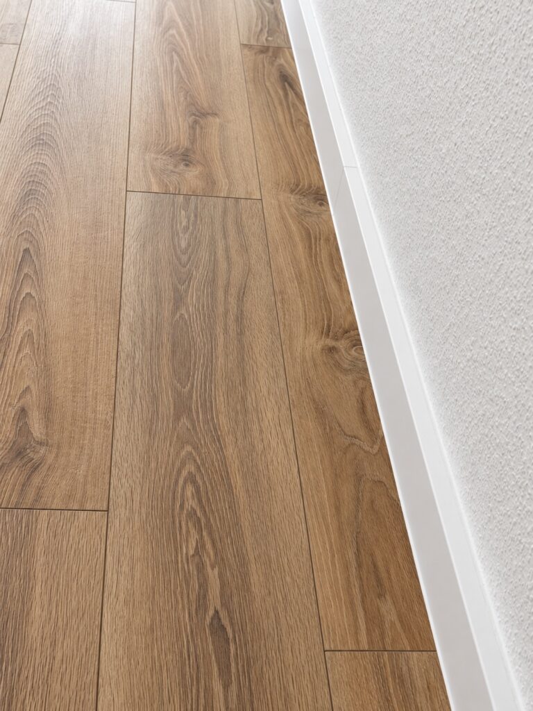 Gerader Wandabschluss mit weißer Sockelleiste und braunem Boden